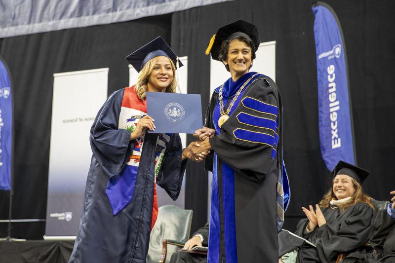 Chancellor Pyati poses with a graduate on stage